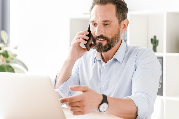 Knappe zakenman die op mobiele telefoon spreekt