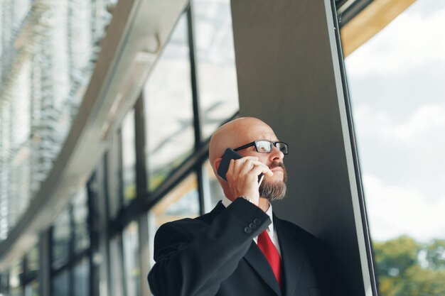 Knappe zakenman die smartphone in het bureau gebruiken