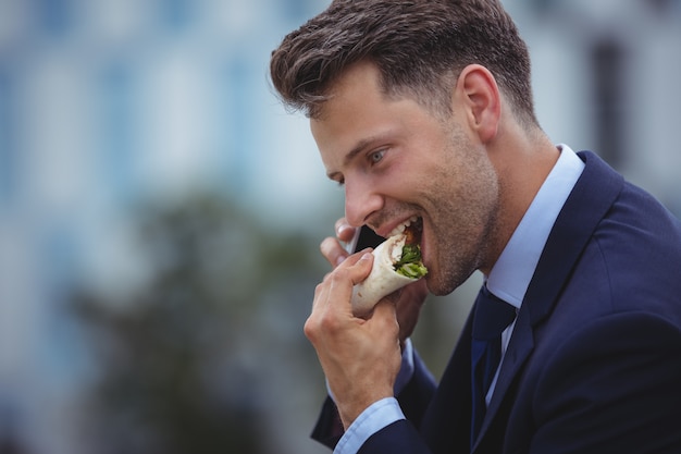 Knappe zakenman die snacks eet