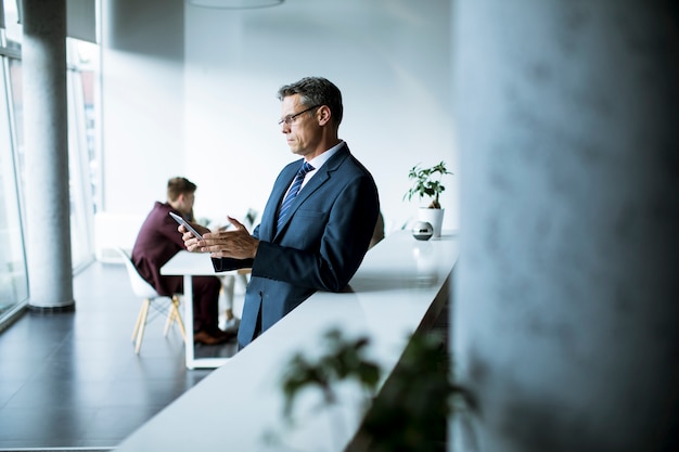 Knappe zakenman die zijn tablet in het bureau gebruiken