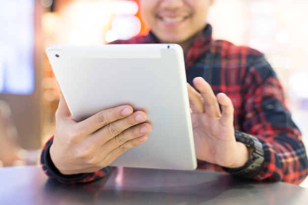 Knappe zakenman in een gebruikende tablet blij in coffeeshop. Aziatische man