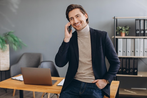 Knappe zakenman in pak praten aan de telefoon in het moderne kantoor