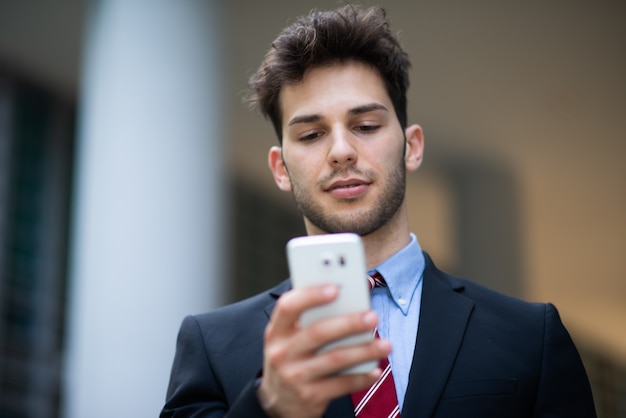 Knappe zakenman met behulp van een mobiele telefoon