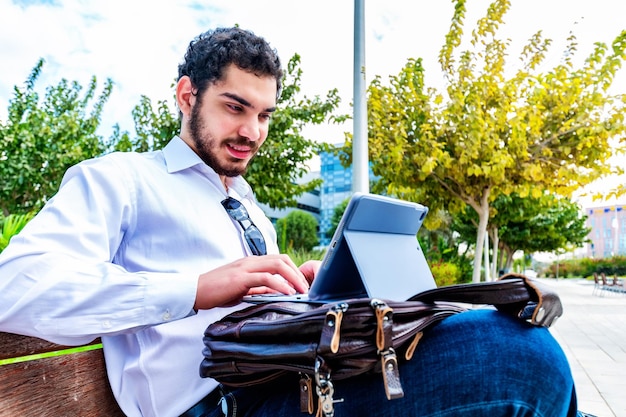 Knappe zakenman met behulp van laptop in het park