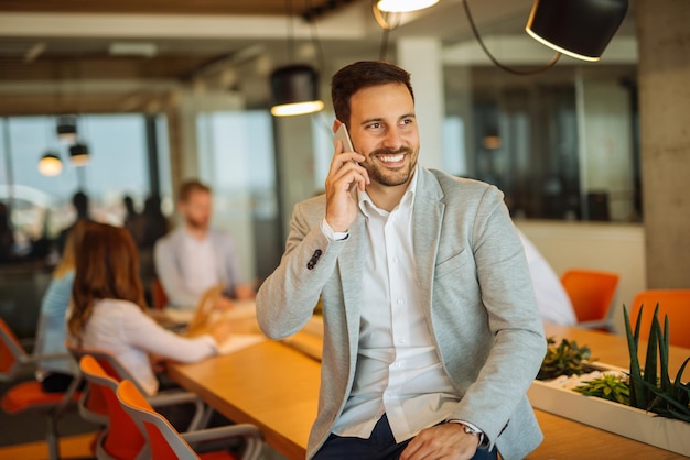 Knappe zakenman praten aan de telefoon op kantoor.