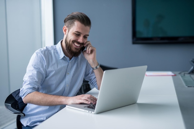 Knappe zakenman praten op de mobiele telefoon in een kantoor