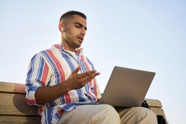 Knappe zakenman uit het Midden-Oosten die een laptop gebruikt en een videogesprek heeft dat online werkt