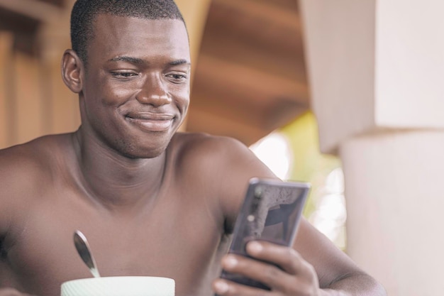 Knappe zwarte man genieten van ontbijt met smartphone