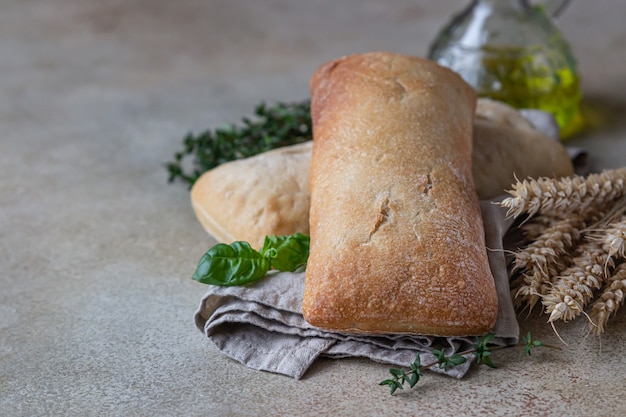 Knapperig Italiaans ciabattabrood op linnenservet, steenachtergrond.