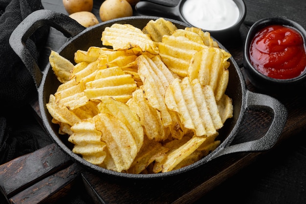 Knapperige aardappelchips. Plakjes aardappel, geroosterd met zeezout, op zwarte houten