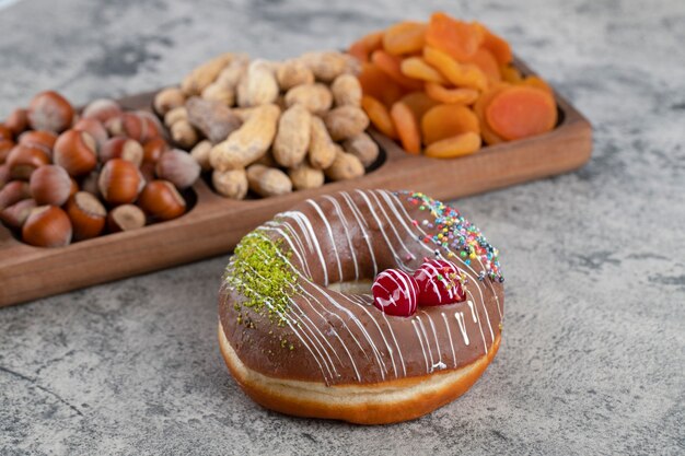 Knapperige crackers met hazelnoten en pinda's in de dop en donut met chocoladeglazuur.