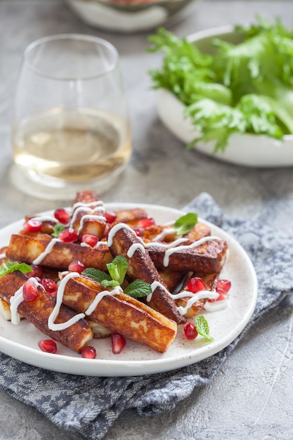 Knapperige halloumi kaasstengels met yoghurtsaus, granaatappelpitjes en muntblaadjes