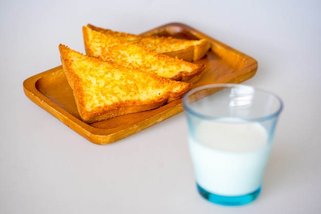 Foto knapperige kaas toast op houten plaat op witte achtergrond met melk in glas