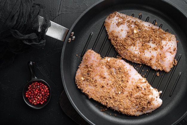 Foto knapperige knoflookkip rauwe ingrediënten op ijzeren koekenpan over zwarte achtergrond plat gelegd