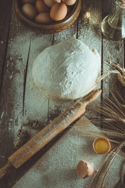 Фото Замешанные колосья из пшеничной булавки и бутылка масла на старом деревенском столе крупным планом