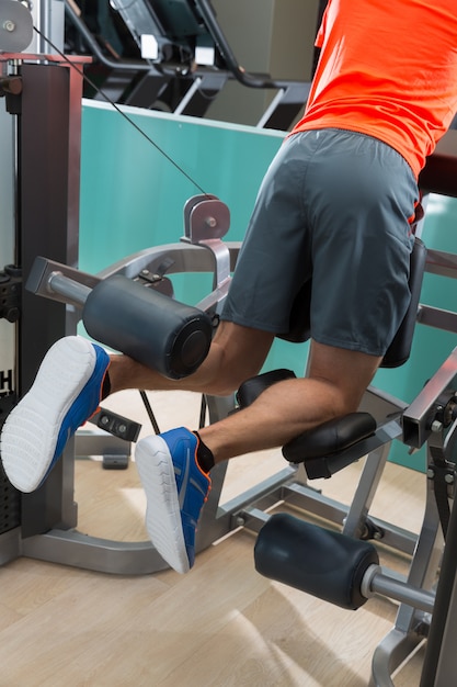 Kneeling leg femoral curl man at gym