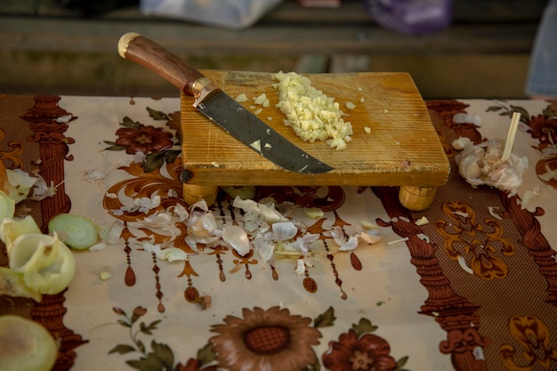 A knife and a chopped garlic in wooden board