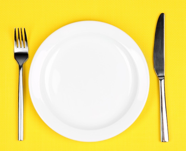 Фото Цветная тарелка ножа и вилка на цветном фоне