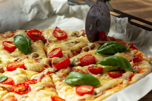 Knife cuts fresh homemade pizza on a baking sheet