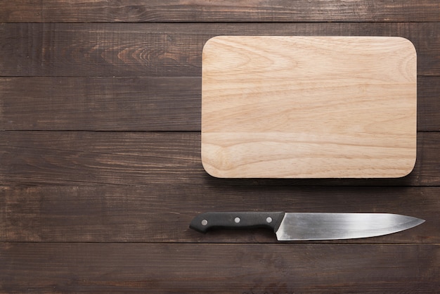 Knife and cutting board on the wooden background