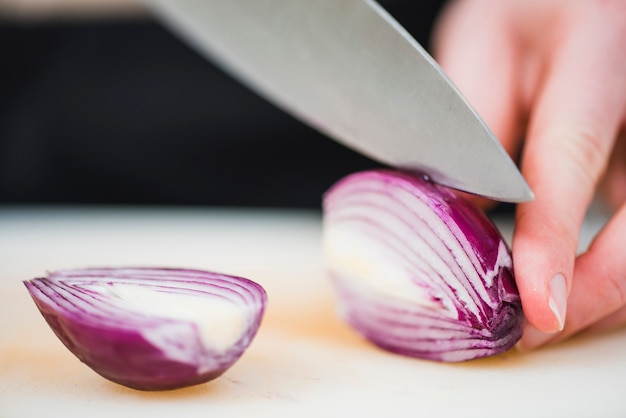 Photo knife cutting onion in halves on board