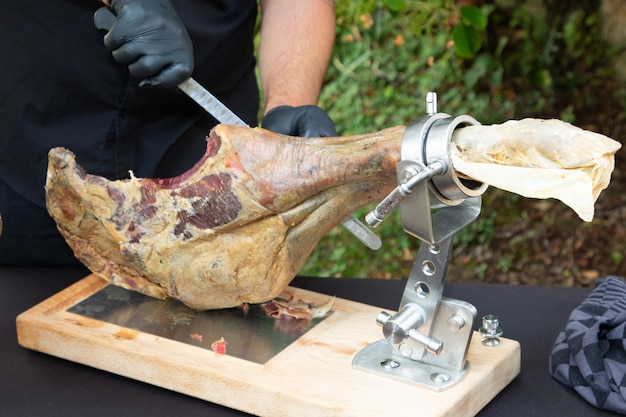 Knife cutting serrano chef man hand slicing of italian dry cured ham prosciutto