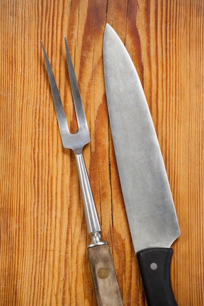 Knife and fork against wooden board