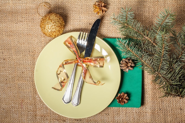 Knife and fork on white plate and green napkin in New Year's scenery