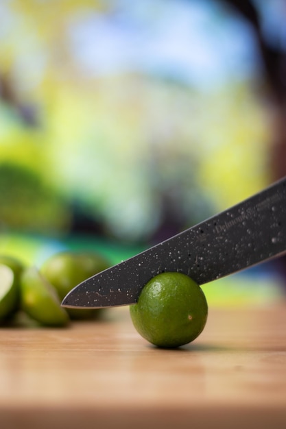 A knife is cutting a lime on a cutting board.