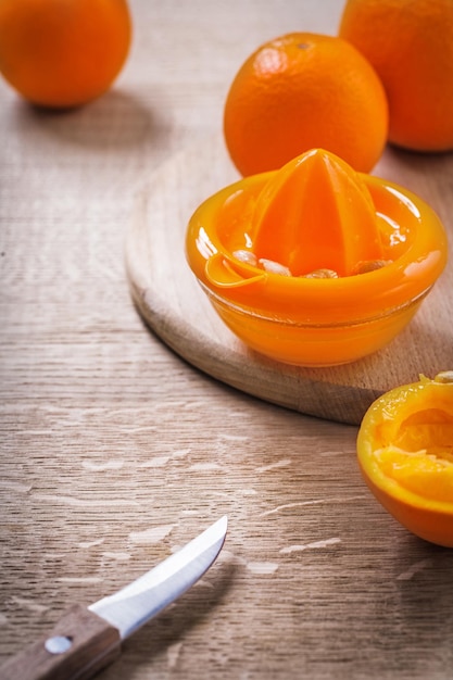 Knife juicer oranges on wood table