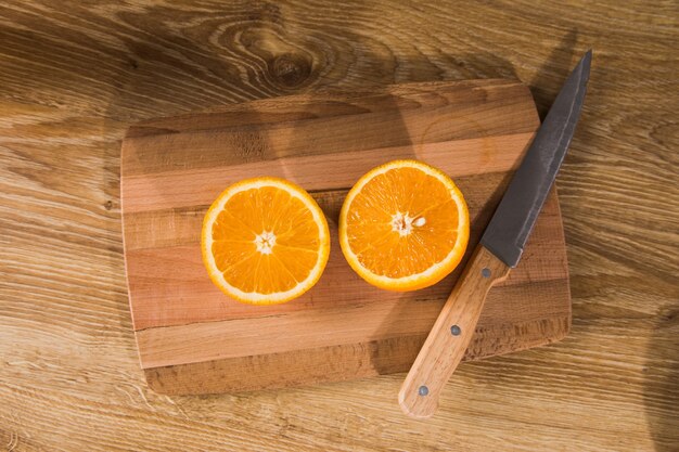 A knife and an orange on a wooden table