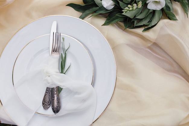 Photo knife, white plate and fork on beige tablecloth