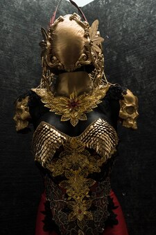 Рыцарь, золотые доспехи и металлические детали ручной работы, у него золотой нагрудник из чешуи дракона со шлемом из готических фигур и красными перьями.