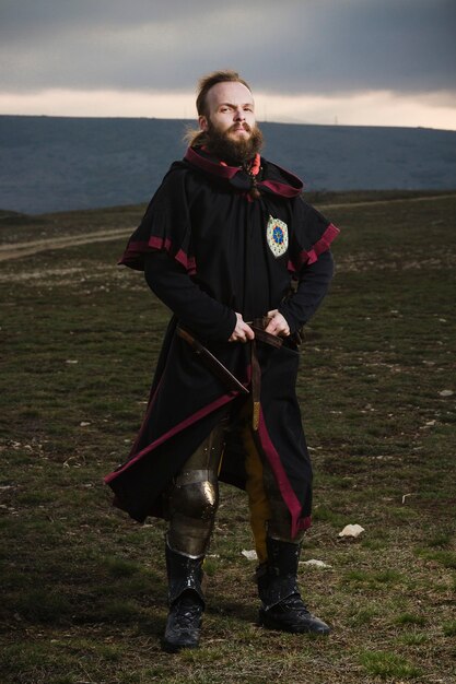Photo knight in a tunic against the background of the evening horizon.