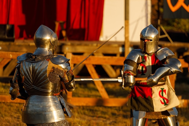 Knights in medieval armor fight at the tournament in the summer. High quality photo