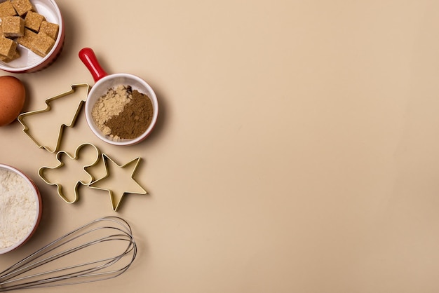 Knip de vorm van een peperkoekkoekje in de vorm van een kerstboom, sterren en peperkoekmannetje en ingrediënten voor koekjes, eieren, meel, suikerkruiden, bovenaanzicht, kopieerruimte