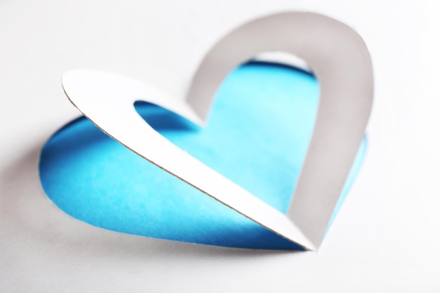 Knip een wit papieren hart op een blauwe achtergrond uit