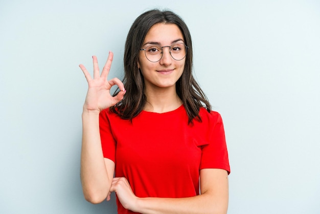 Knipoogt met een oog en houdt een goed gebaar met de hand vast