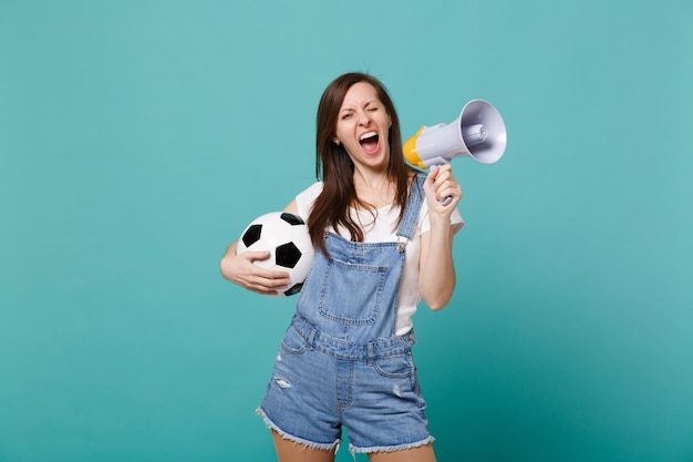 Knipperende meisje voetbalfan schreeuw in megafoon ondersteuning favoriete team met voetbal geïsoleerd op blauwe turkooizen achtergrond. Mensen emoties sport familie leisure lifestyle concept. Bespotten kopie ruimte.