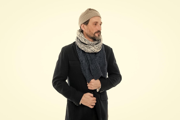 ニットアクセサリー成熟した男寒い冬の天気スタイル冬のコレクション男は暖かさと快適さをお楽しみください寒い冬の条件のためのカジュアルなコート帽子とスカーフの白い背景を身に着けているハンサムな男