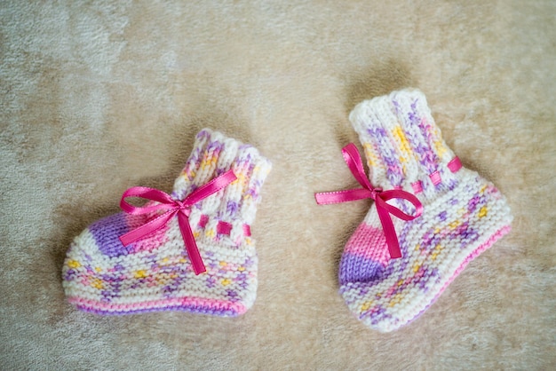 Knitted baby socks on a wooden background.