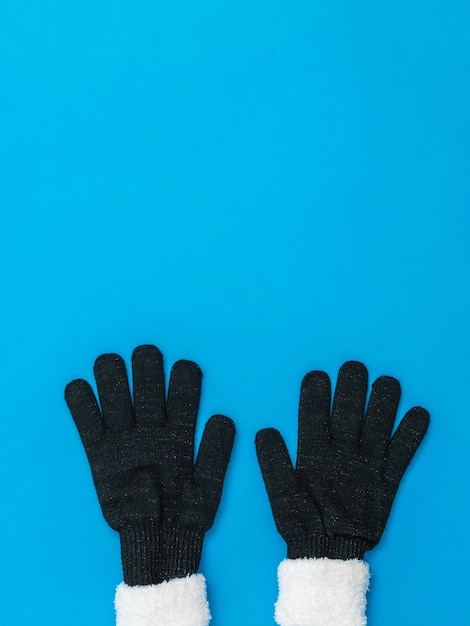 Photo knitted black women's gloves bottom blue background. the concept of hope and meeting. fashion women's accessories.