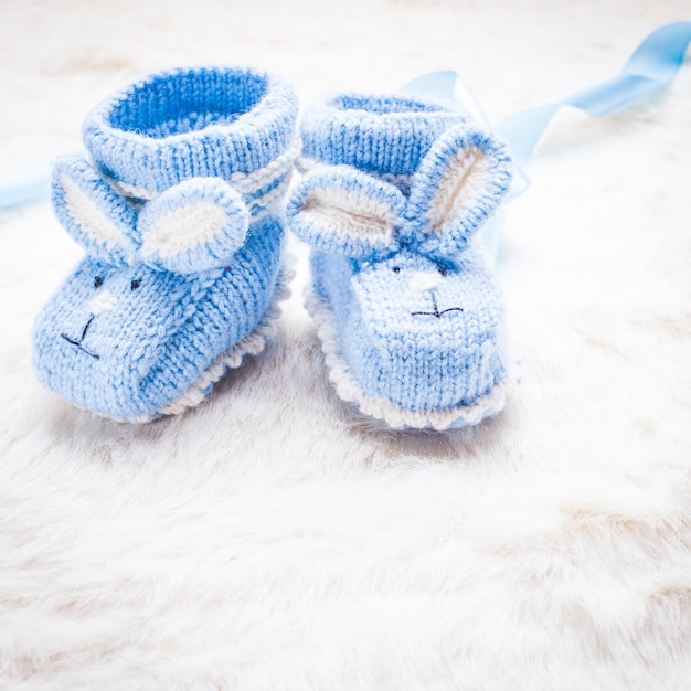 Knitted blue baby booties with rabbit muzzle for little boy