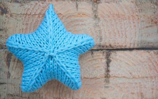 Knitted blue star on a light wooden background