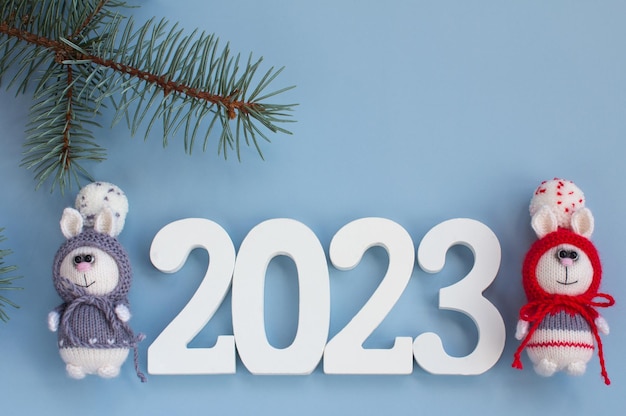 크리스마스 트리가 있는 나무 배경에 선물이 있는 니트 토끼 2023년 수제 토끼의 새해