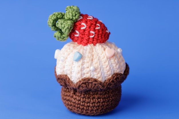 Knitted cake with strawberries on a blue background