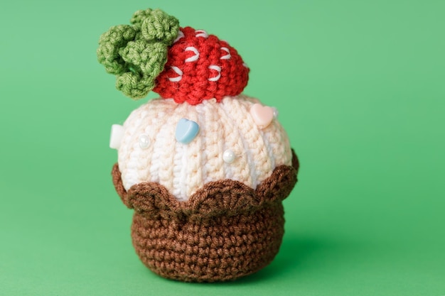 Knitted cake with strawberries on a green background