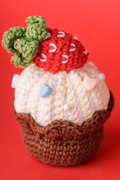 Knitted cake with strawberries on a red background