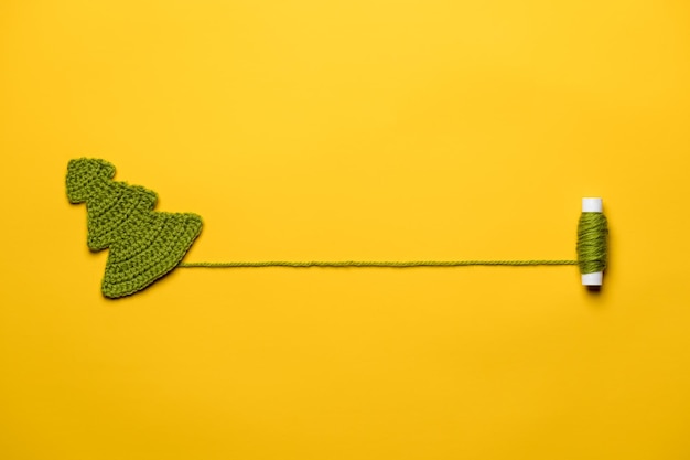 Photo knitted christmas tree a symbol of the new year with a spool of thread with a place for text