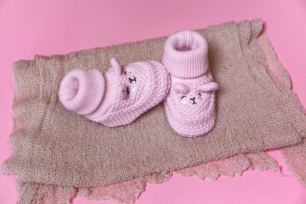 Knitted crochet newborn shoes on a pink background waiting for a baby girl